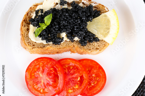 Black caviar and butter on bread with tomatoes on plate closeup