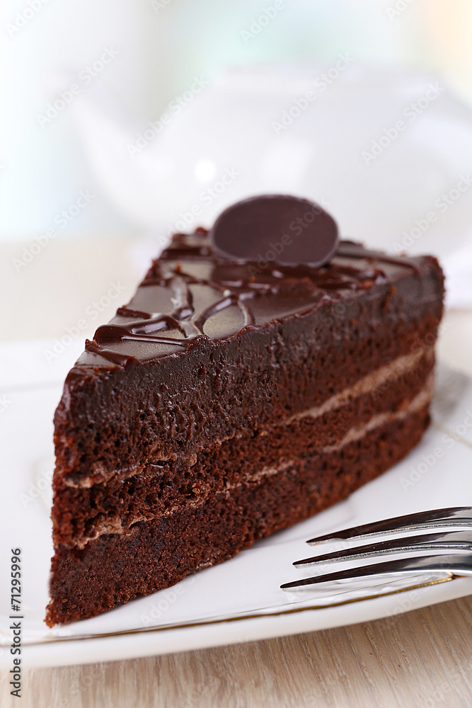 Piece of chocolate cake on plate on light background