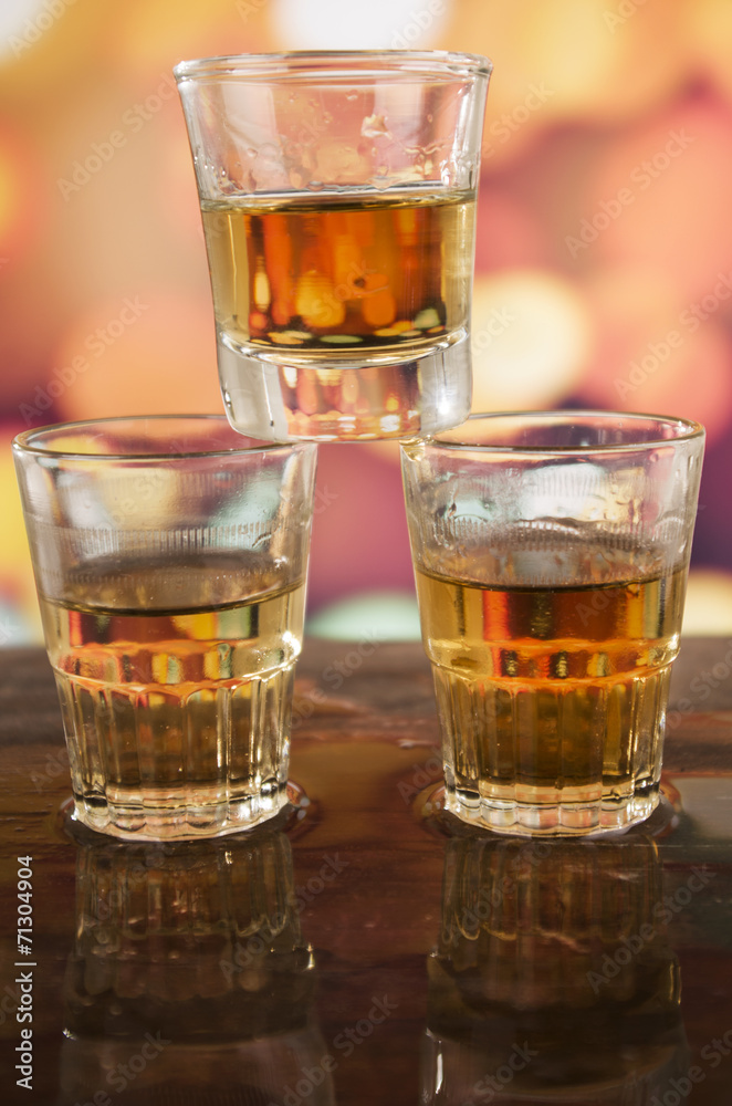 glass of rum whiskey over defocused lights background