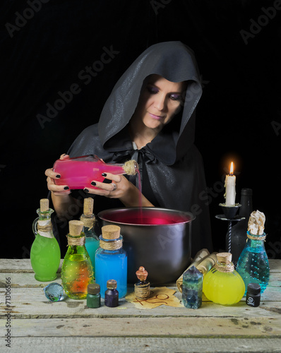 Foto Halloween witch with magic pot and shining bottles