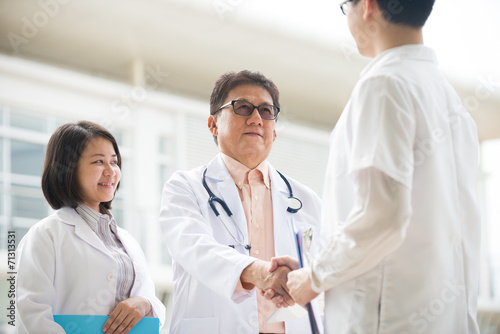 Asian medical team of doctors shaking hands inside hospital buil