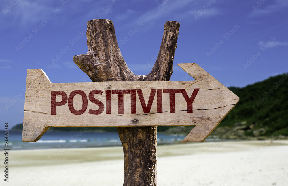 Positivity wooden sign with a beach on background