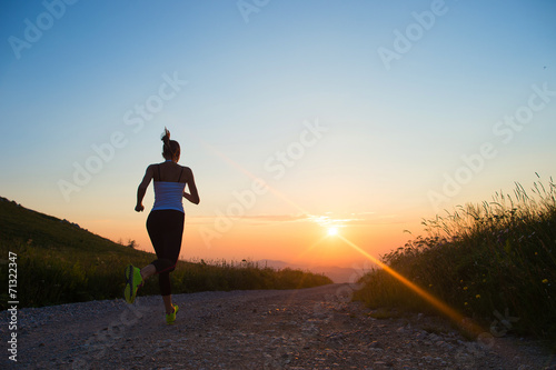 woman running on a mountain road at summer sunset