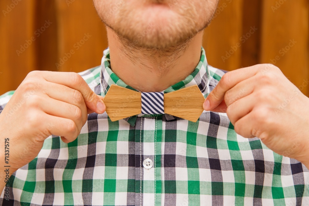 Fashion young man correcting his casual wooden bowtie