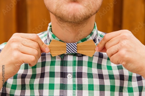 Fashion young man correcting his casual wooden bowtie