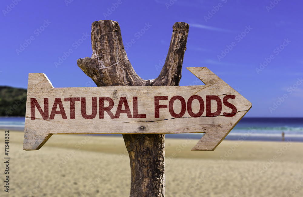 Natural Foods wooden sign with a beach on background
