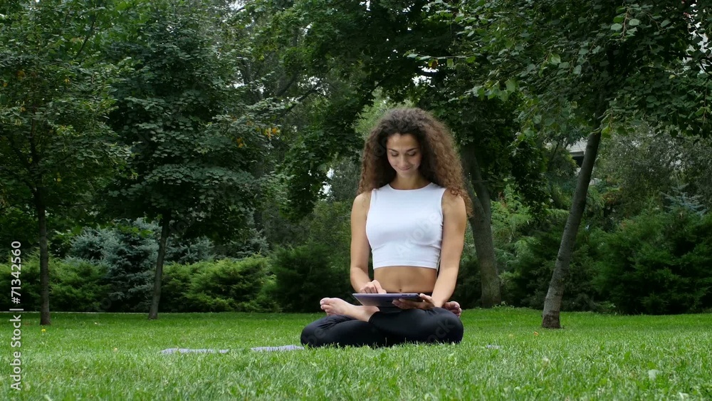 Young woman yoga in the park working on a tablet pc Young woman yoga in the park working on a tablet pc