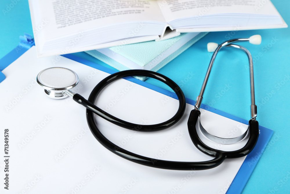 Medical stethoscope with books and folder on blue background Medical stethoscope with books and folder on blue background