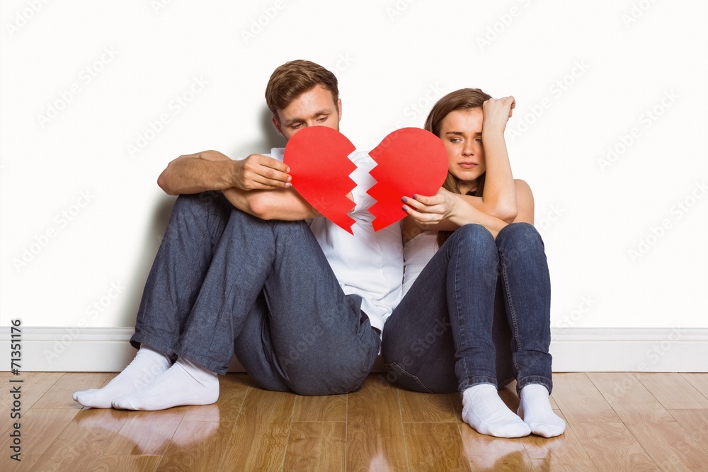 Young couple holding broken heart - obrazy, fototapety, plakaty 