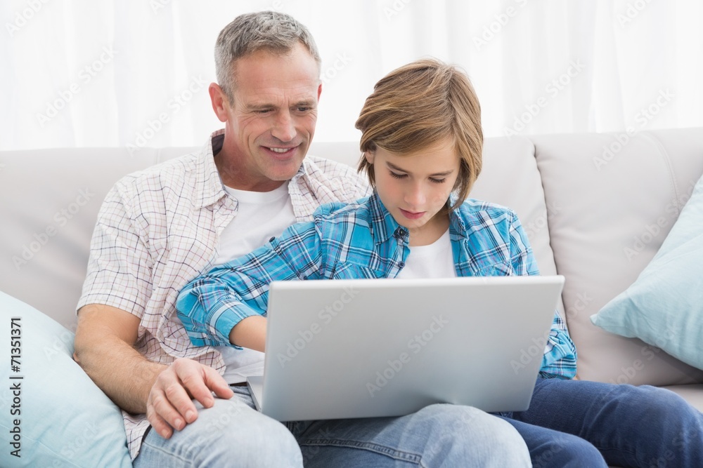 Father with son sitting on the couch using laptop