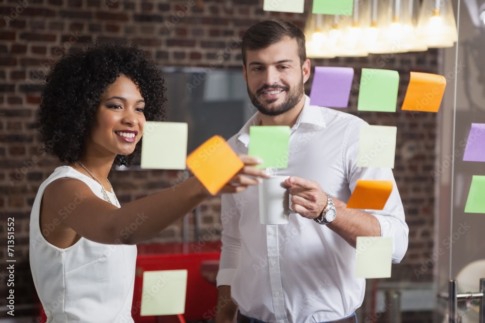 Casual business team looking at sticky notes Casual business team looking at sticky notes