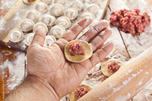 Dumplings. Dough with meat filling on the cook's hands.
