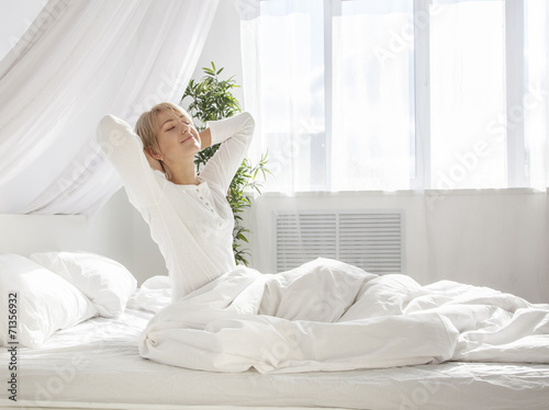 beautiful woman has woken up and is sitting on a white bed