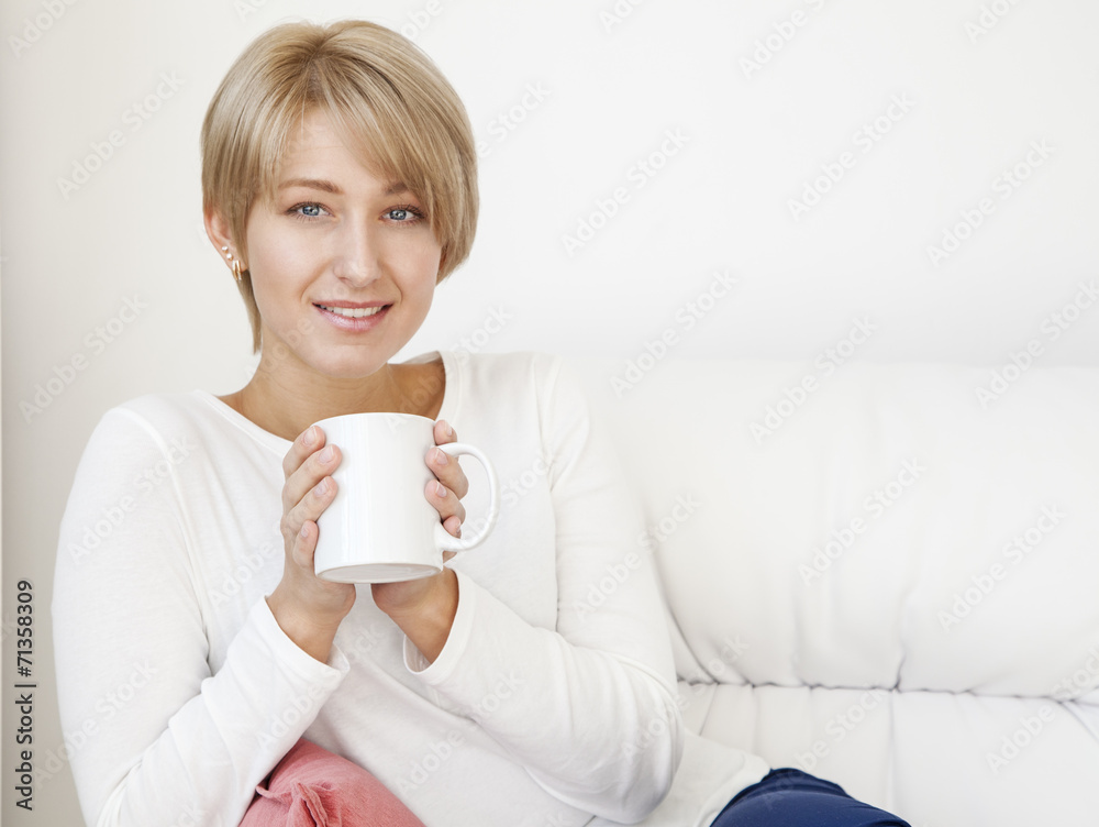 beautiful woman with a cup on a white couch