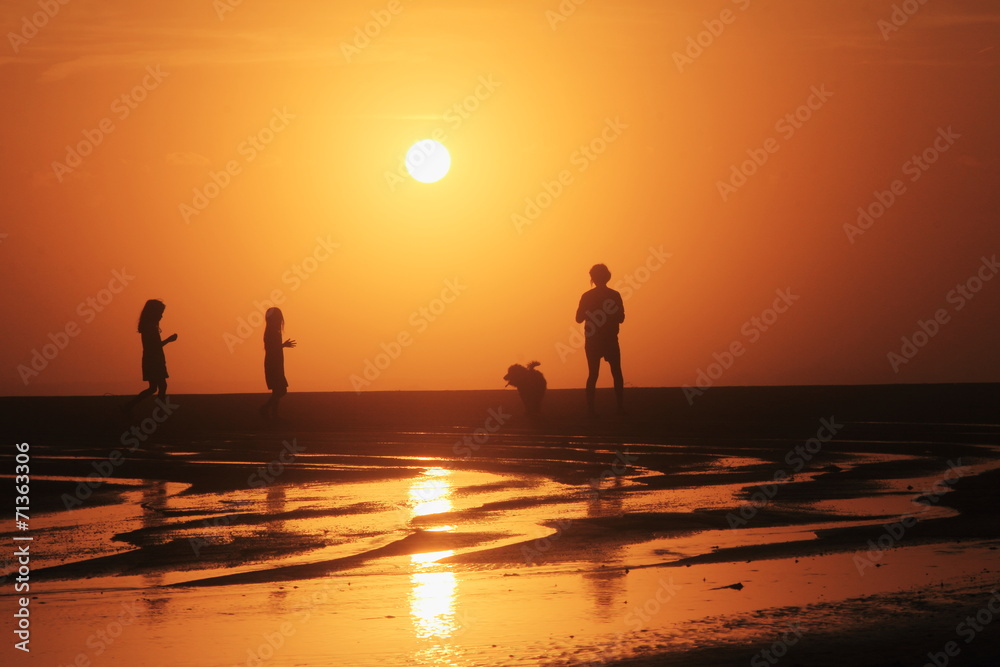 夕方の浜辺を散歩する親子のシルエット