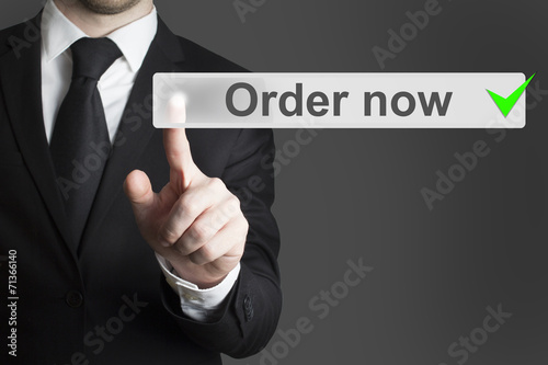 businessman in black suit pushing button order now
