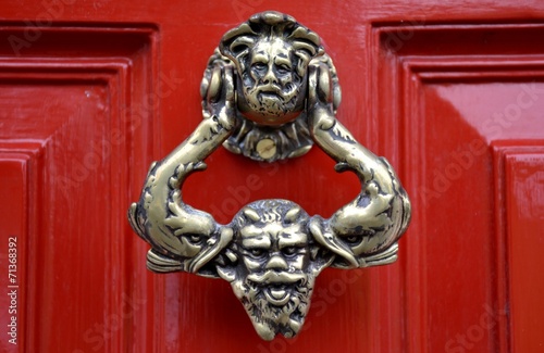 Old door knocker and red background © louizaphoto