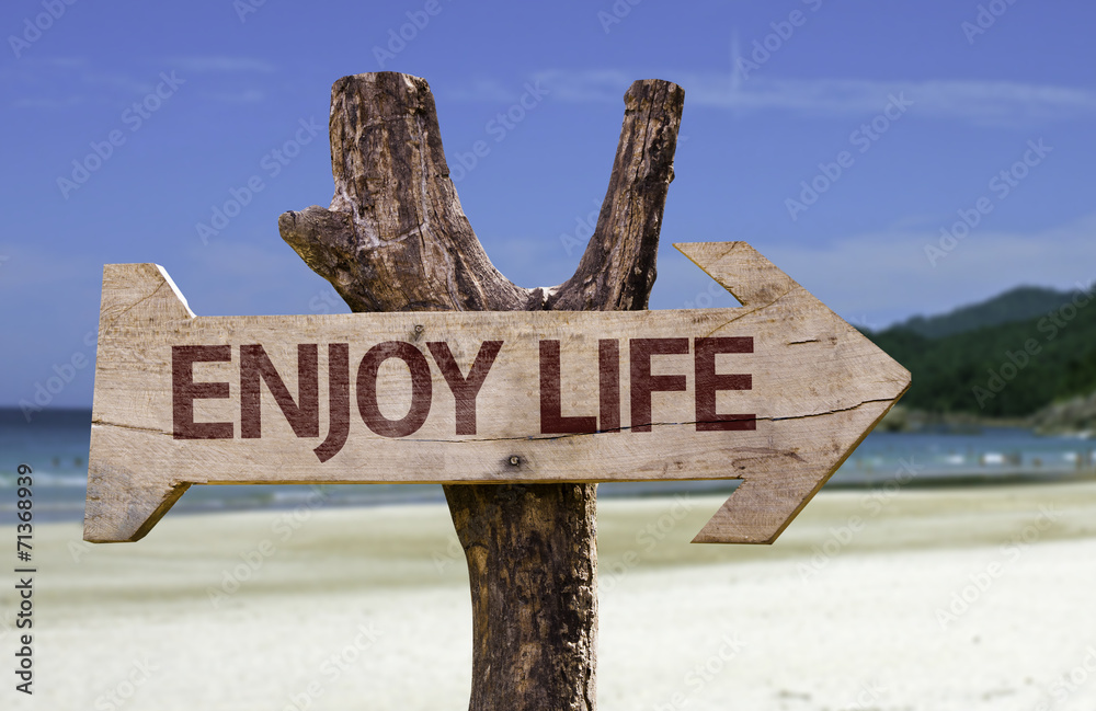 Enjoy Life wooden sign with a beach on background
