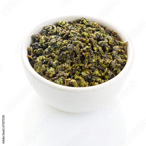 Tieguanyin tea leaves in a ceramic bowl on white background