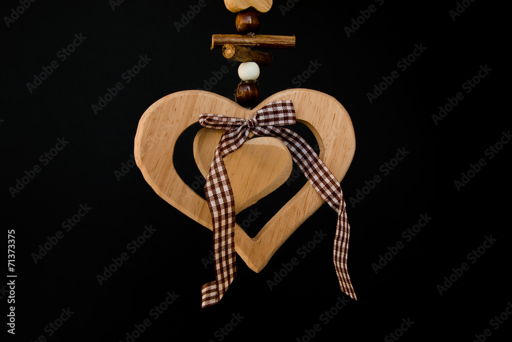Wooden heart on a rope with wooden balls, a bow in the middle