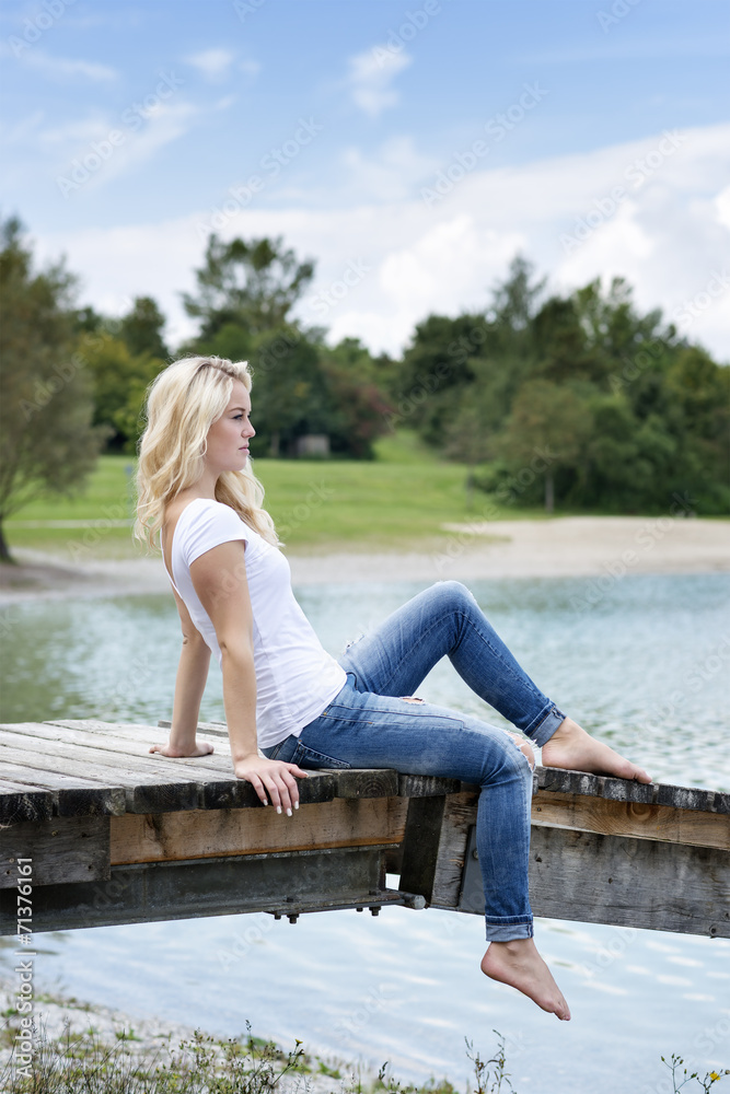 Blond woman sitting on a jetty