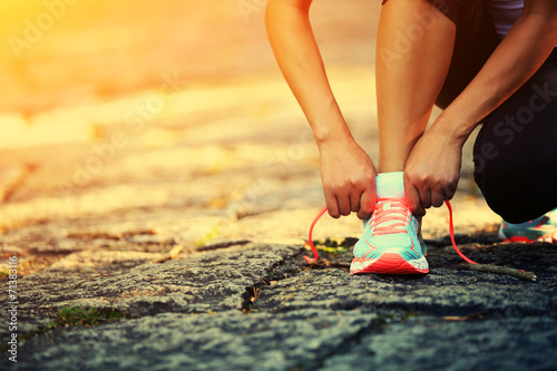 Fotografie woman runner tying shoelace on stone trail
