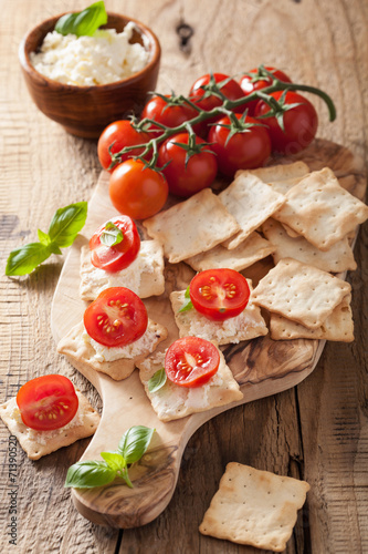 crackers with soft cheese and tomatoes. healthy appetizer