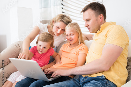 Family Using Laptop On Sofa
