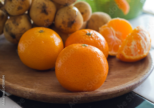 fresh orange tangerines and thai fruit on wood plate