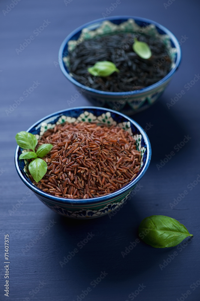 Red and black rice kernels in ceramic pialats, vertical shot Red and black rice kernels in ceramic pialats, vertical shot