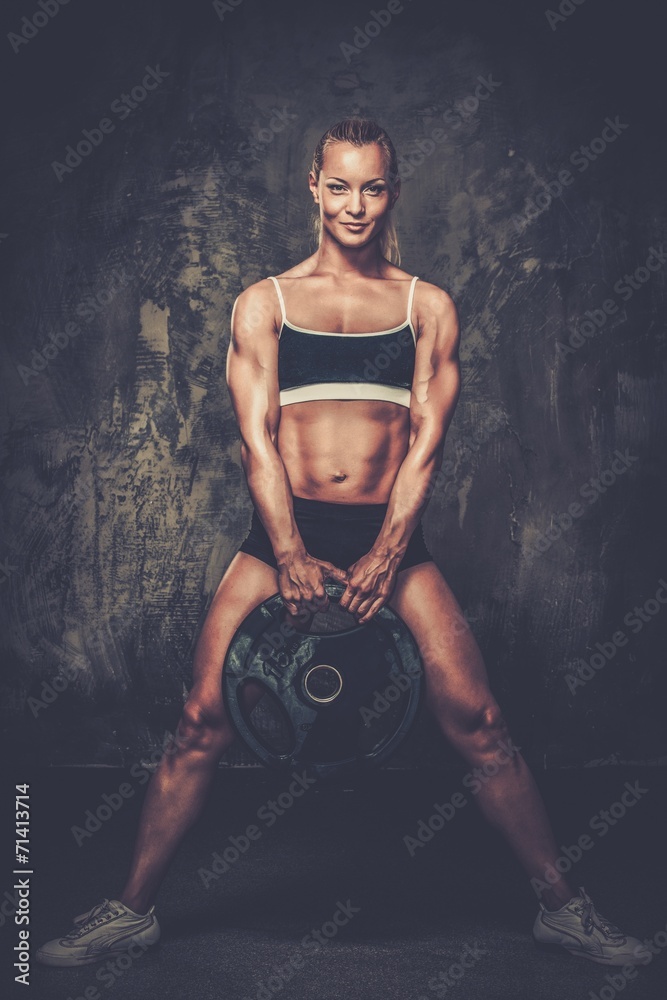 Fototapeta premium Beautiful muscular bodybuilder woman with weights