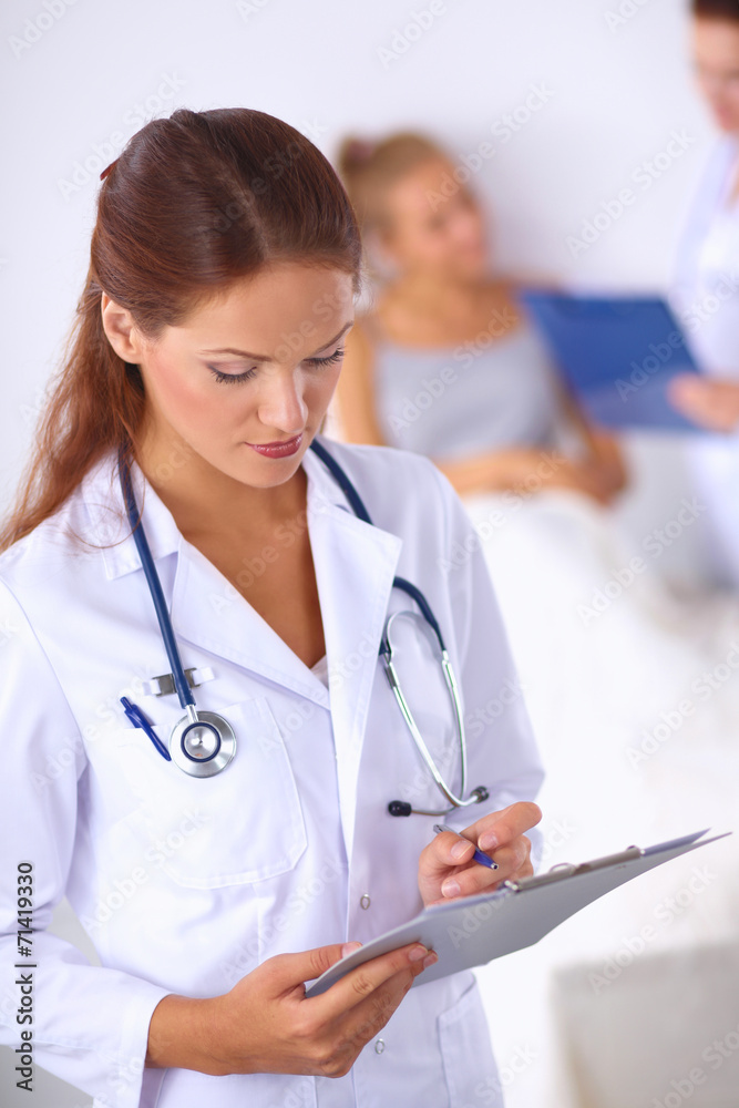 Smiling female doctor with a folder in uniform standing at Smiling female doctor with a folder in uniform standing at