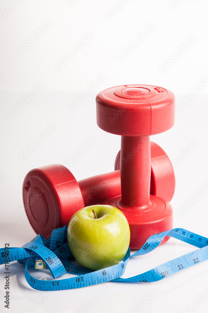 Red dumbbells weight with measuring tape and green apple Red dumbbells weight with measuring tape and green apple
