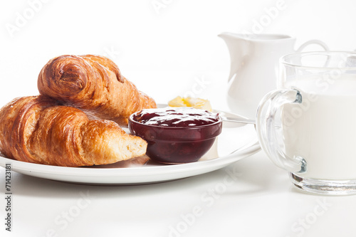 Fresh croissants with butter and a glass of milk