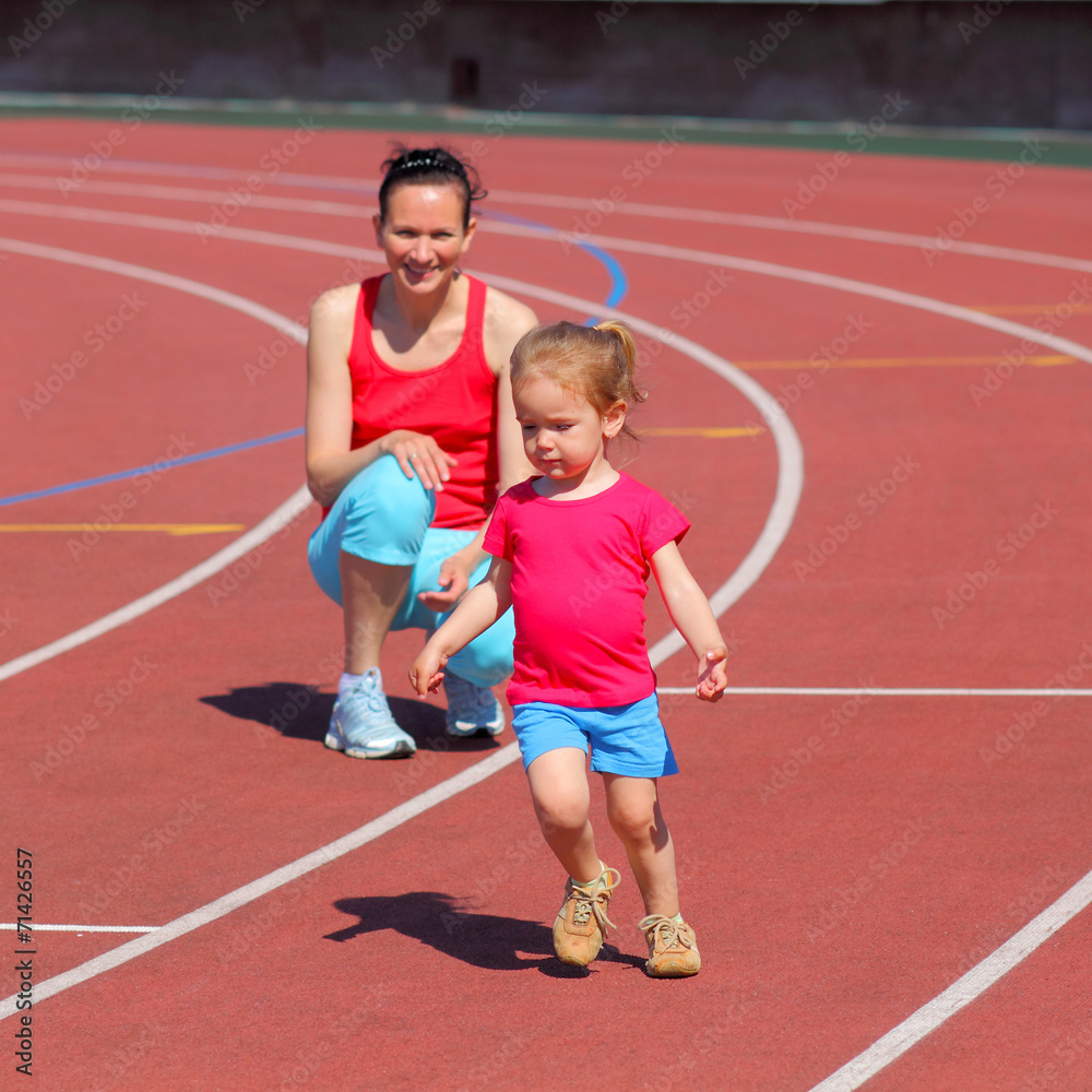 Obraz premium Mother and little daughter are running in the stadium.