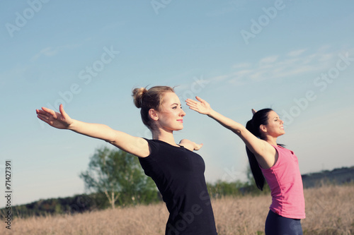 Two women doing yoga outdoors. 
