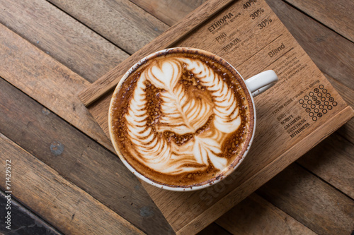 Cup of hot latte art coffee on wooden table