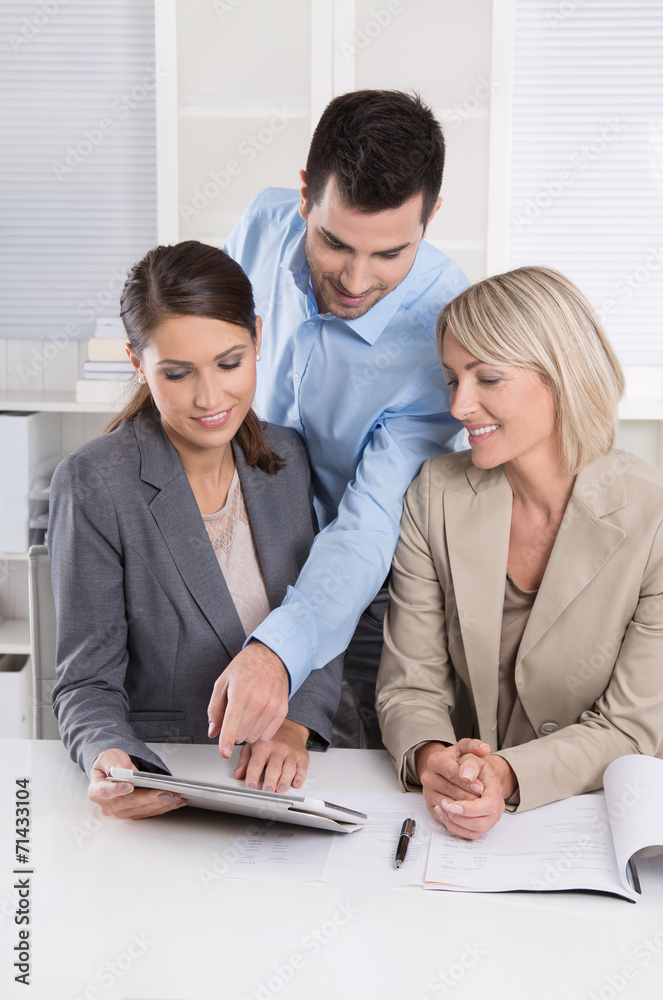 Erfolgreiches Business Team blickt auf einen Tablet PC Erfolgreiches Business Team blickt auf einen Tablet PC