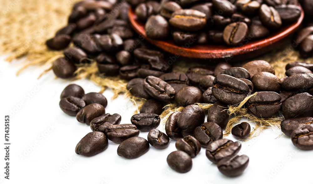 coffee beans on sacking and wood spoon, white background