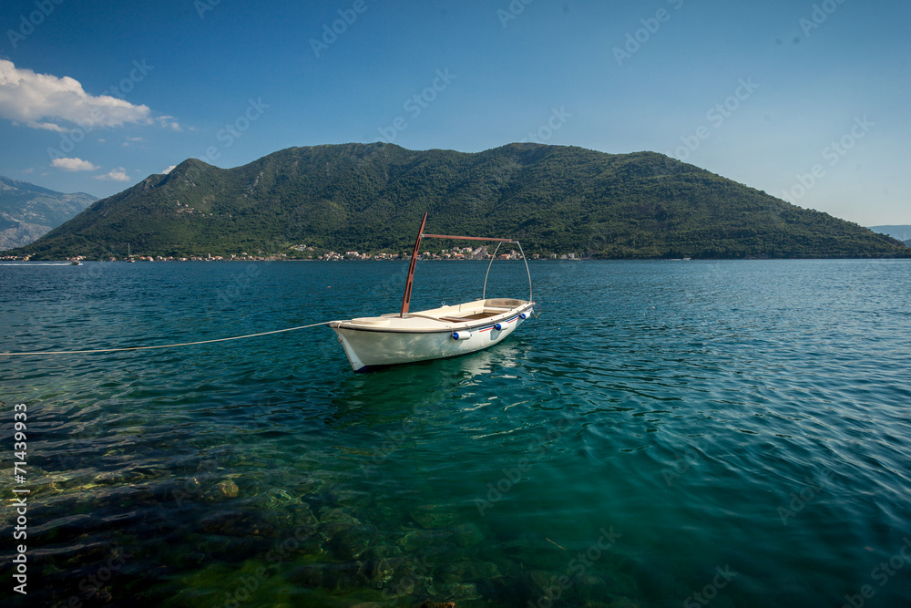 Kotor bay with moored white wooden rowboat