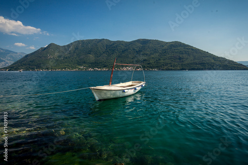 Kotor bay with moored white wooden rowboat