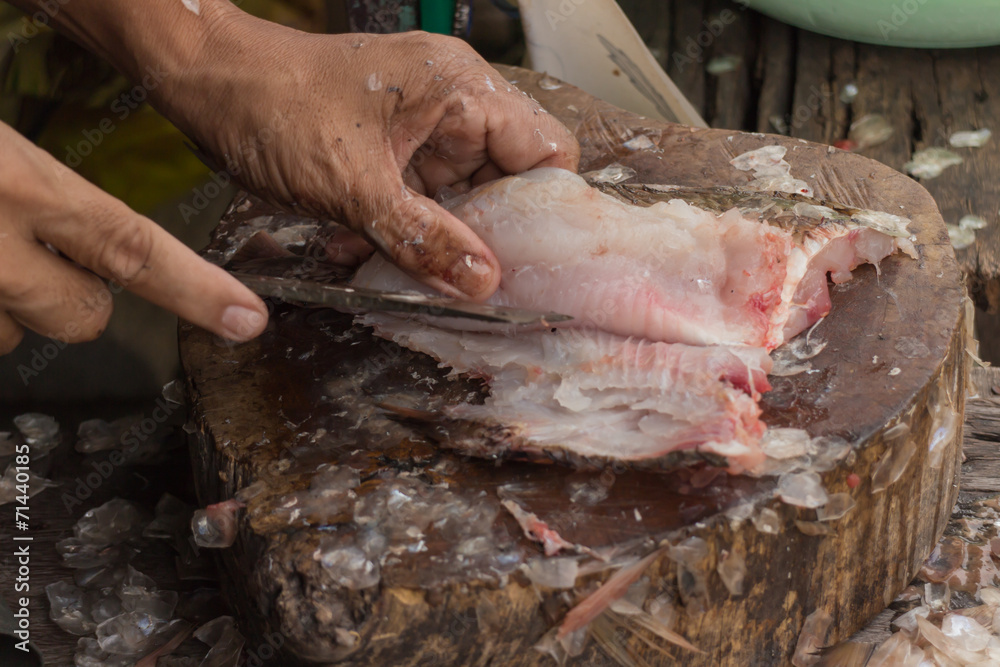 hands cutting a fresh fish on a cutting board