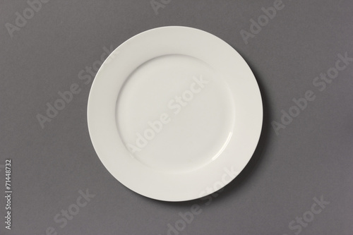 Top view of white empty plate on grey background