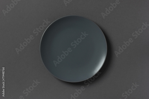Top view of grey empty plate on dark background