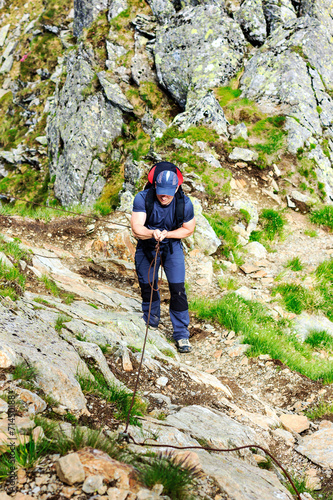 Young man hiking on difficult mountain trail with hanging cable