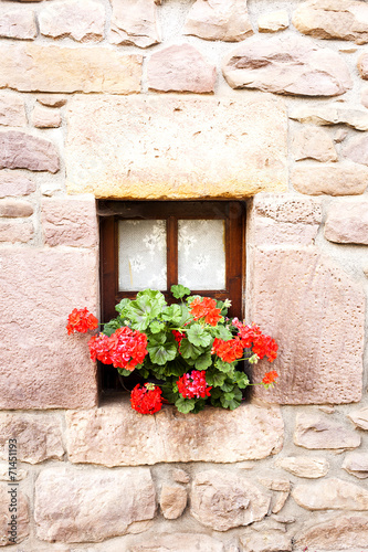 Fototapeta Naklejka Na Ścianę i Meble -  ventana con visillos y flores en pared de piedra.