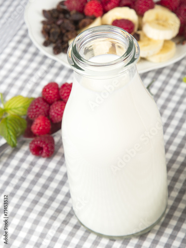 bottle of fresh milk and fuit: banana, raspberries and raisins