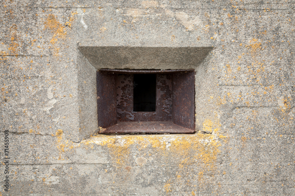 Rusted loophole in old concrete bunker wall