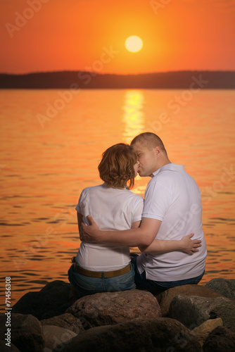 Young couple enjoying a kiss during sunset on the beach