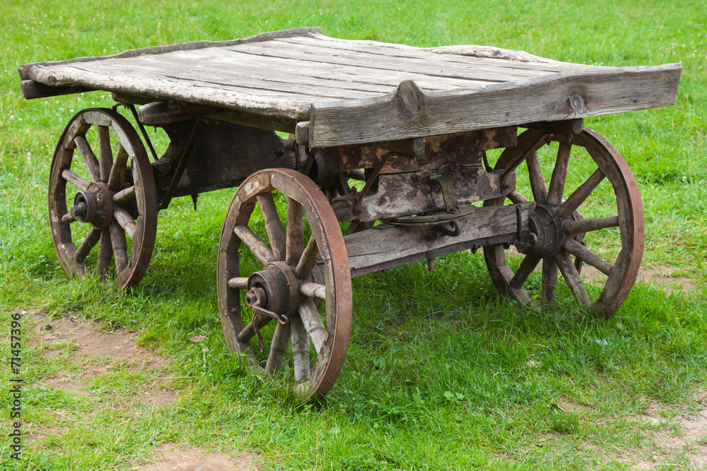 Empty old rural wooden wagon stands on green summer grass
